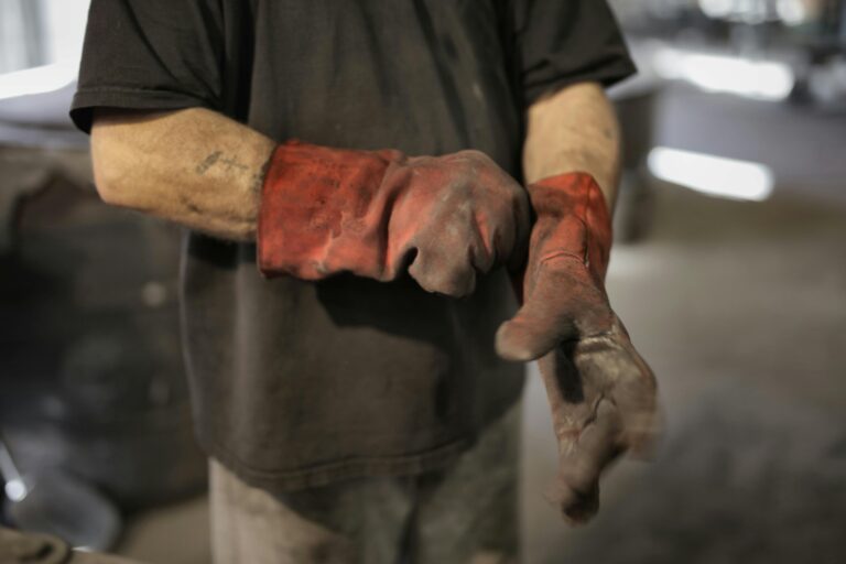 From above of crop male fitter in shabby heavy duty gloves in workshop